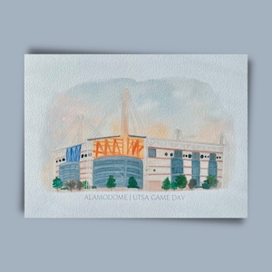 May include: A watercolor painting of the Alamodome, a large stadium in San Antonio, Texas. The painting is done in a light blue, orange, and white color scheme. The text "ALAMODOME | UTSA GAME DAY" is written at the bottom of the painting.