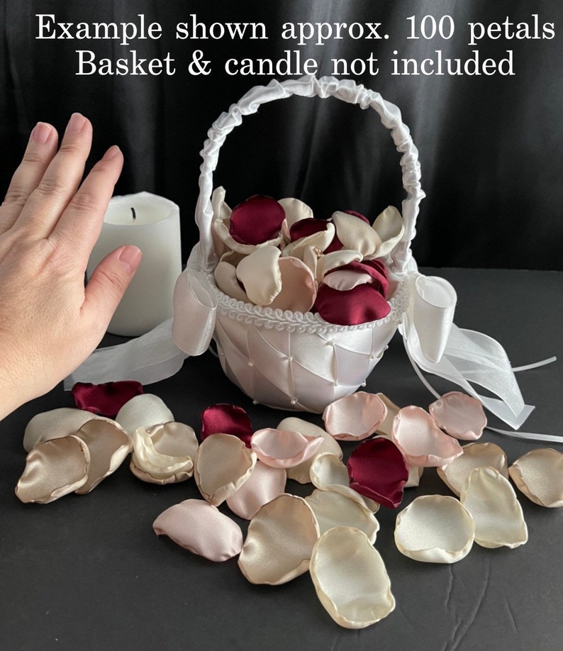 Puede incluir: Una colecci&oacute;n de p&eacute;talos de flores artificiales en tonos burdeos, crema y rosa suave. El texto en la imagen dice: Example shown approx. 100 petals. Basket & candle not included. Estos p&eacute;talos de tela est&aacute;n esparcidos sobre una superficie.