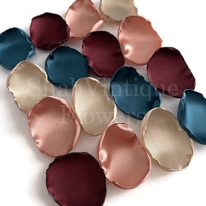 May include: Assortment of silk flower petals in burgundy, teal, blush pink, and cream colors. The petals are arranged in a scattered pattern on a white background.