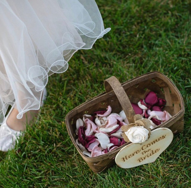 May include: A wooden basket filled with pink and burgundy flower petals. A sign attached to the basket reads "Here Comes The Bride".