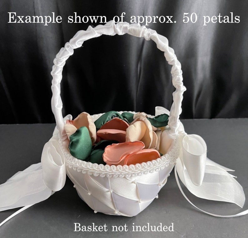 Puede incluir: Una cesta de sat&eacute;n blanco con asa fruncida, borde trenzado y lazos laterales, llena de aproximadamente 50 p&eacute;talos de flores de seda en tonos verde oscuro, rosa empolvado y crema. El texto dice: Example shown of approx. 50 petals. Basket not included.
