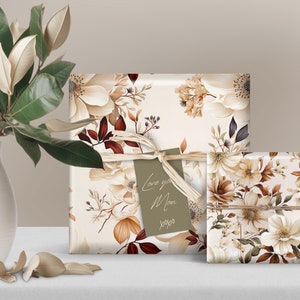 May include: Two gift boxes wrapped in white paper with a floral pattern in shades of brown, cream, and beige. The larger box has a brown tag with the text "Love you Mom xoxo".
