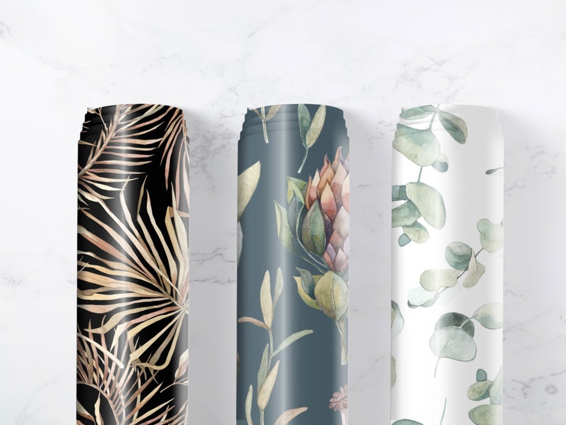 May include: Three rolls of fabric with different floral patterns. The first roll features a black background with gold palm leaves. The second roll has a dark blue background with a floral pattern of pink and green flowers. The third roll has a white background with a green eucalyptus leaf pattern.