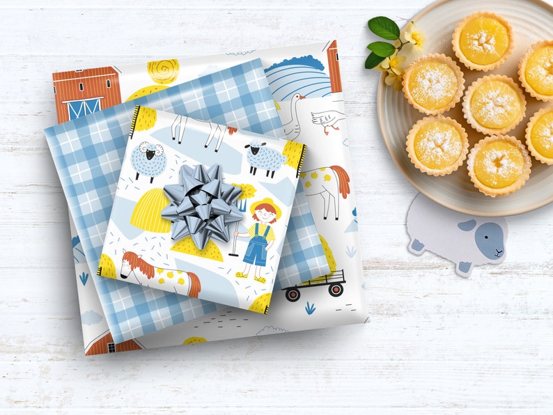 May include: A stack of three gift wrap papers with a farm theme. The top paper features a blue and white plaid pattern, the middle paper has a white background with yellow hay bales, a blue and white plaid border, and illustrations of farm animals, and the bottom paper has a white background with a red barn, a blue and white plaid border, and illustrations of farm animals. The papers are tied together with a silver bow.