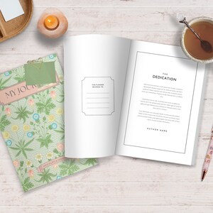 May include: A green journal with a floral pattern and the text "My Journal" on the cover. The journal is open to a blank page with a dedication page on the right side. The dedication page has the text "The Dedication" and "Author Name".