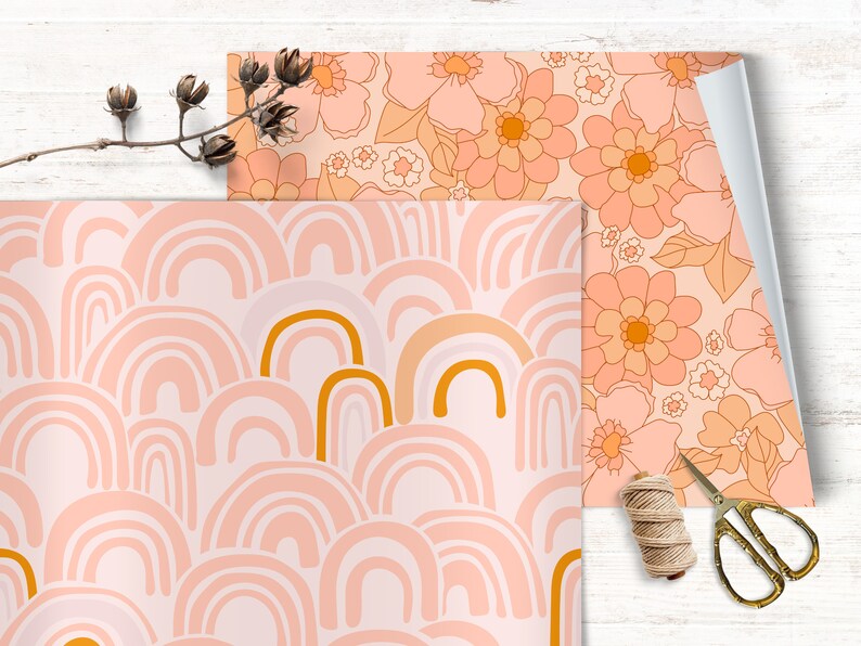 May include: Two sheets of wrapping paper with different patterns. One sheet features a pink and orange floral design. The other sheet features a pink and gold rainbow pattern.