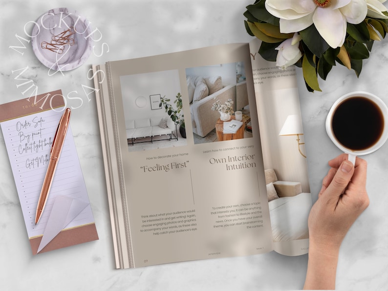 May include: Open magazine with a beige cover featuring the text "Feeling First" and "Own Interior Intuition". The magazine is on a white marble surface with a cup of coffee, a notepad, a pen, and a flower.