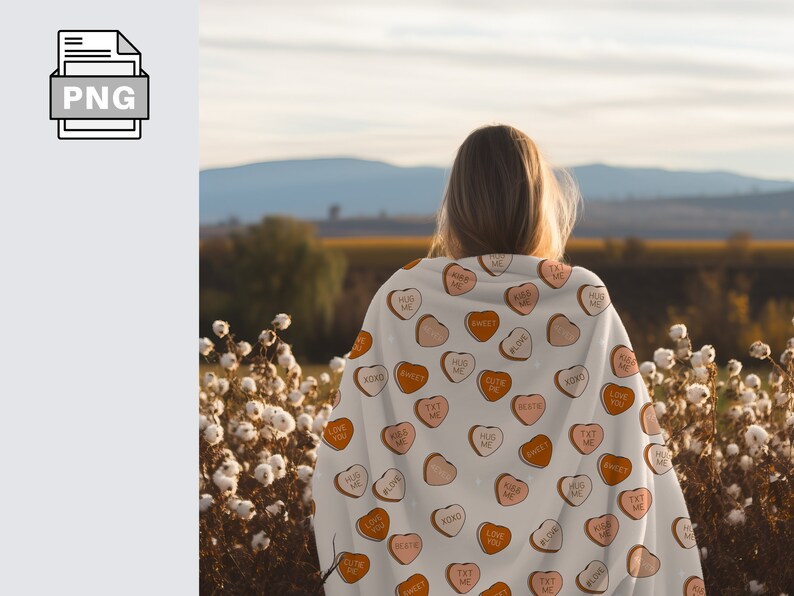 May include: A white blanket with a pattern of pink and orange candy hearts. The hearts have various messages on them, including "Love You", "Hug Me", "Sweet", "XOXO", "Cute Pie", "Text Me", and "Kiss Me".