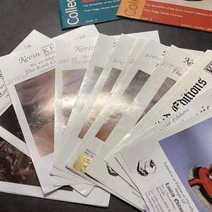 May include: A selection of printed ephemera, including brochures and newsletters, are fanned out on a dark surface. The publications feature the text "Kevin KF" and "Editions", with images and text. Some have handwritten prices.