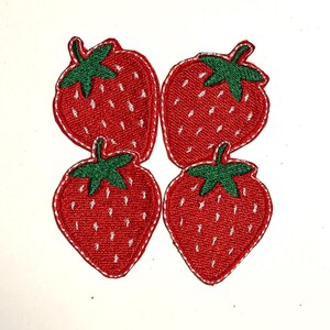 May include: Four embroidered strawberry patches arranged in a square formation. Each patch features a bright red fruit body with a green stem at the top and small white stitched details representing seeds, finished with a white stitched border.
