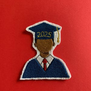 May include: A blue and white embroidered patch of a graduate wearing a cap and gown. The cap has the year 2025 embroidered on it.