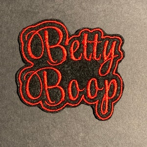 May include: A black and red embroidered patch with the text "Betty Boop" in a stylized font.