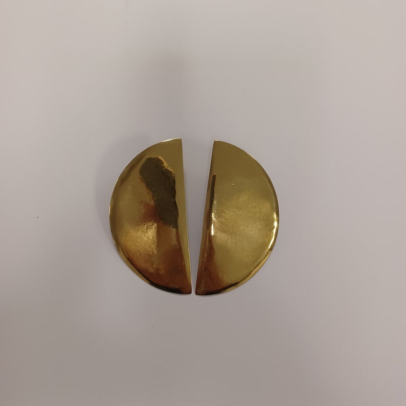 May include: A pair of gold-toned earrings, each shaped like a half-circle.