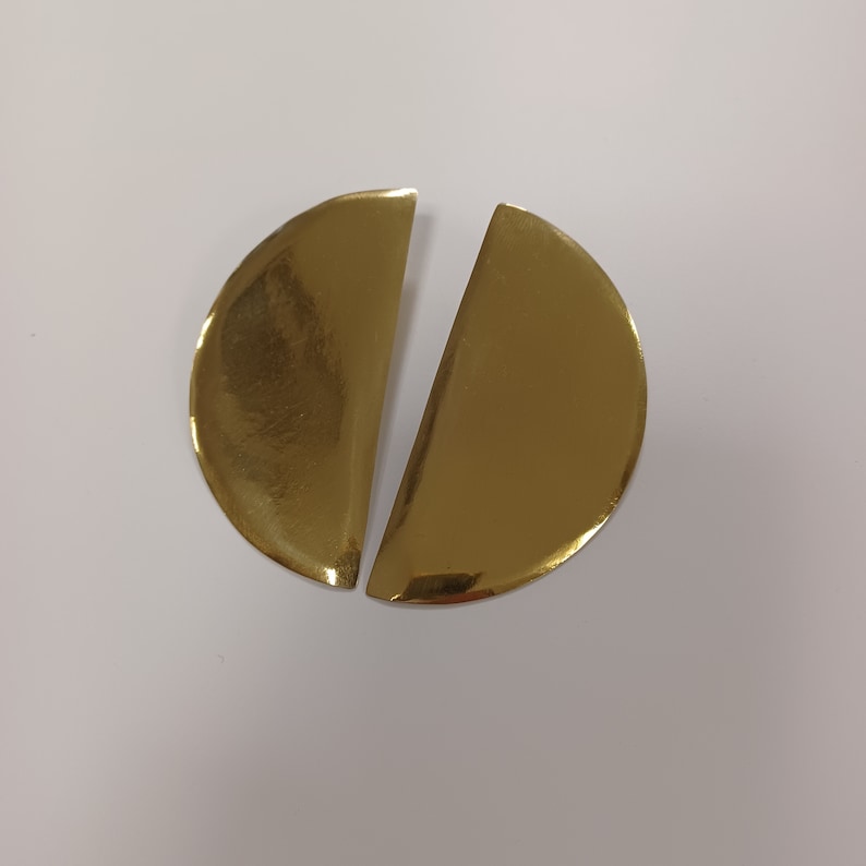 May include: A pair of gold-colored earrings, each shaped like a half circle.