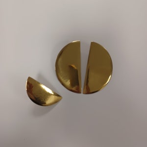 May include: Three gold-colored metal half-circle shapes. Two of the shapes are larger and fit together to form a circle. The third shape is smaller and is a half-circle.