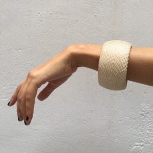 Könnte beinhalten: Ein weißes Lederarmband mit Schlangenhautmuster.