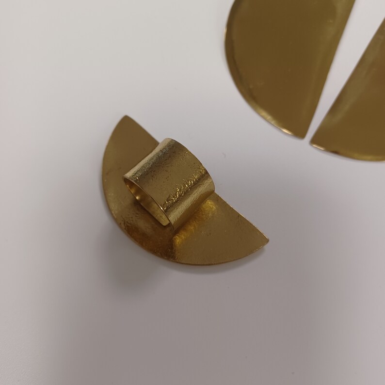 May include: A set of three gold-toned metal half-circle shapes. One shape has a ring attached to it.