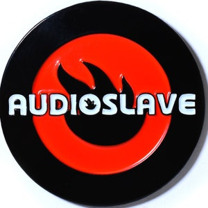 May include: A black and red circular button with the word "AUDIOSLAVE" in white letters and a black flame design.