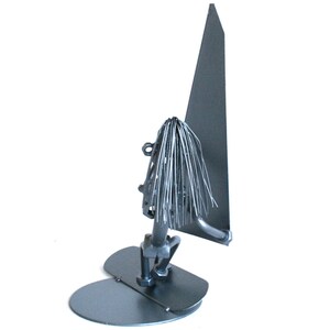 May include: A silver metal sculpture of a person windsurfing. The sculpture is made of thin metal strips and has a simple, abstract design.