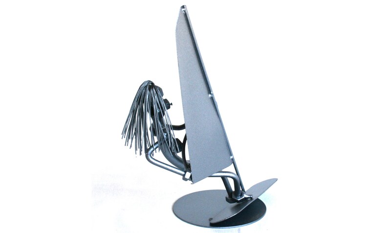 May include: A silver metal sculpture of a person windsurfing. The sculpture is made of recycled metal and is a unique and whimsical piece of art.