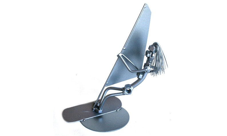 May include: A silver metal sculpture of a person windsurfing. The sculpture is made of nuts, bolts, and wire. The person is holding a sail and is standing on a board.