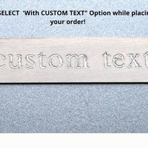 May include: Close-up of a silver metal tag with the words "custom text" engraved on it.