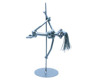 May include: A silver metal sculpture of a person in a dancing pose, holding onto a pole. The sculpture is on a round base.