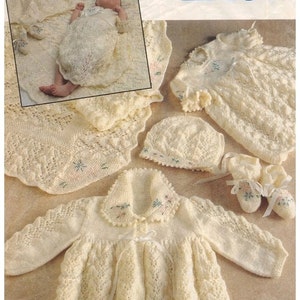 Puede incluir: Un conjunto de ropa de bebé de ganchillo en color crema, que incluye un vestido, un cárdigan, un gorro y botines. La ropa está decorada con delicados bordados florales. La clasificación de tejido es fácil de tejer con patrones de punto simples.