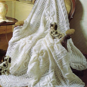 May include: A white crocheted blanket with a delicate floral pattern, draped over a chair. The blanket is made with a fine yarn and features intricate lacework.