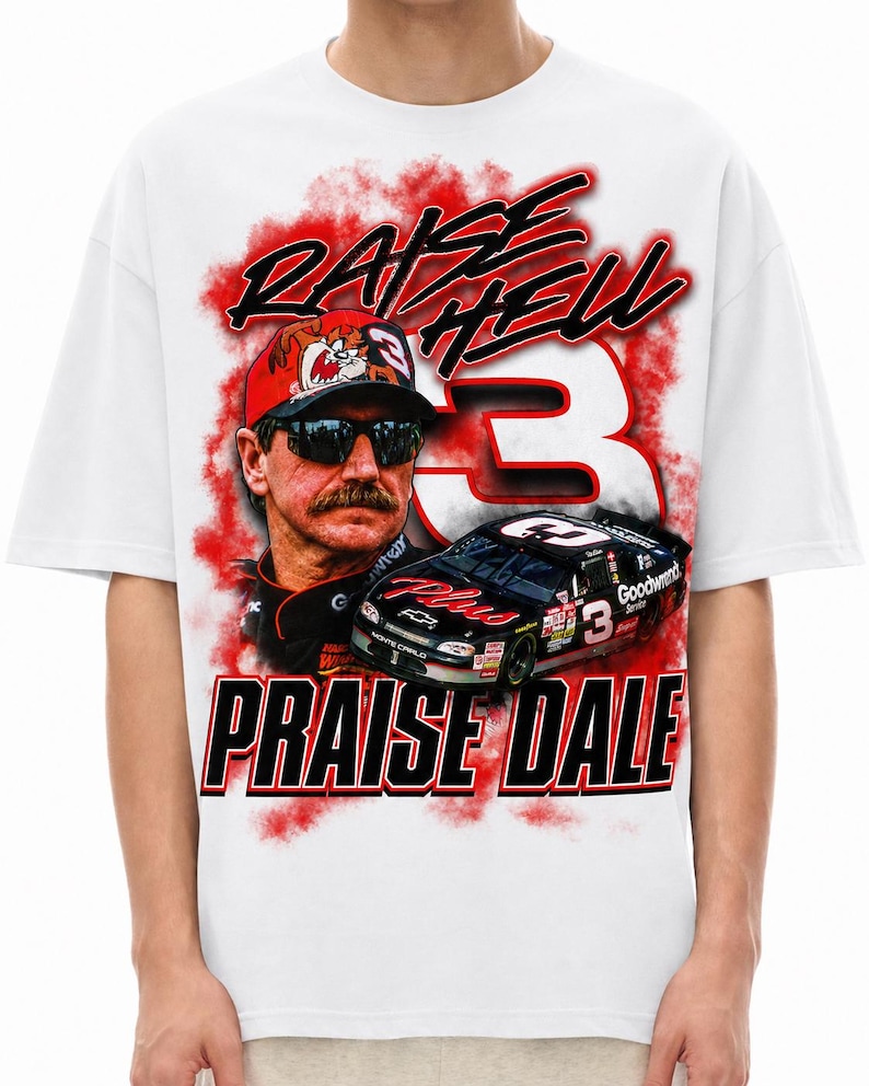 K&ouml;nnte beinhalten: Ein wei&szlig;es T-Shirt mit einem Grafikdruck eines Rennfahrers mit Sonnenbrille und Kappe, einem schwarzen Rennwagen mit der Nummer 3 und roten Raucheffekten. Der Text RAISE HELL und PRAISE DALE ist in fetten schwarzen und roten Buchstaben aufgedruckt.
