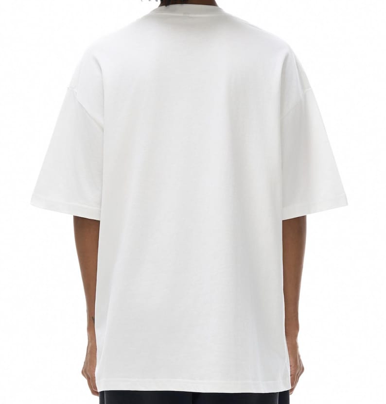K&ouml;nnte beinhalten: Ein schlichtes, wei&szlig;es T-Shirt mit kurzen &Auml;rmeln und Rundhalsausschnitt. Das Kleidungsst&uuml;ck hat eine lockere, entspannte Passform mit &uuml;berschnittenen Schultern und einem geraden Saum. Der Stoff ist einfarbig wei&szlig; und ohne Muster oder Logos.