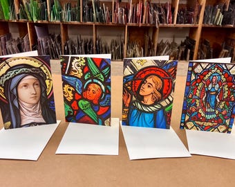 May include: Four blank greeting cards featuring stained glass images of religious figures. The images are colourful and detailed, with a variety of colours including red, blue, green, and yellow.