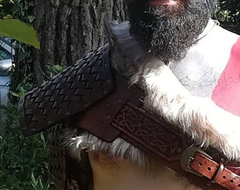 May include: A man dressed as the video game character Kratos, with a white and red face paint, a long black beard, and a leather and fur costume.