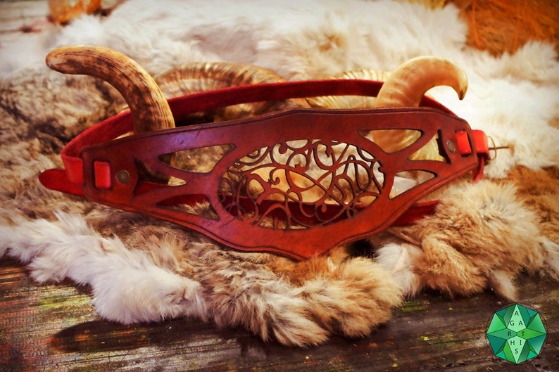 May include: A red leather headband with a decorative cutout design. The headband is adorned with two antler horns.
