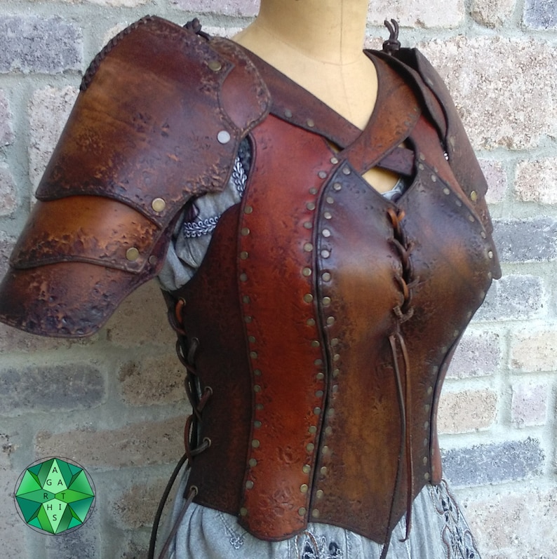 May include: A brown leather armor with a laced front and decorative studs. The armor has a textured surface and a dark brown color.