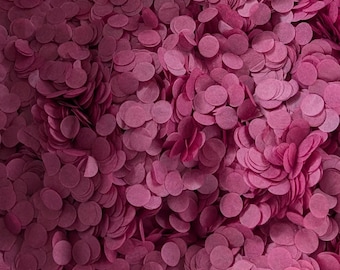Puede incluir: Una gran colección de pequeños confeti de papel circulares en un color magenta intenso o rosa oscuro. Los discos de papel individuales están dispuestos en capas densas, creando una superficie texturizada de formas redondas uniformes.