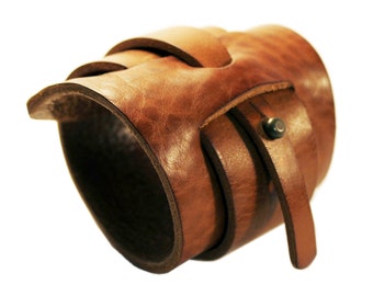 May include: A brown leather bracelet with a braided design and a metal buckle.