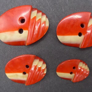 Puede incluir: Cuatro botones vintage de varios tama&ntilde;os. Cada bot&oacute;n tiene forma ovalada con una parte superior roja y una inferior color crema. La secci&oacute;n roja tiene un dise&ntilde;o acanalado. Cada bot&oacute;n tiene dos agujeros para coser.