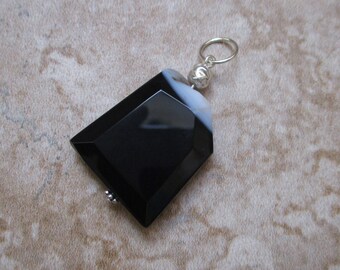 May include: Black and white agate pendant with a silver bail. The pendant is shaped like a rectangle with rounded corners.