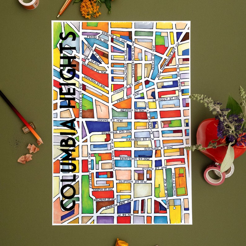 May include: A colorful watercolor map of Columbia Heights, a neighborhood in Washington, D.C. The map shows the streets and blocks of the neighborhood, with each block colored in a different shade. The map is surrounded by a white border.