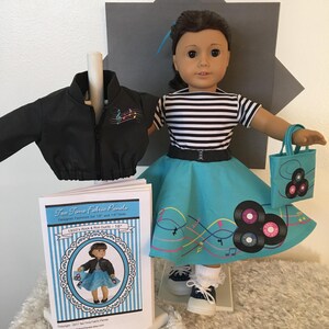 May include: A doll wearing a 1950s-style outfit, including a black jacket, a striped top, and a turquoise skirt with record and music note designs. The doll is holding a matching tote bag. A pattern for the outfit is also visible.