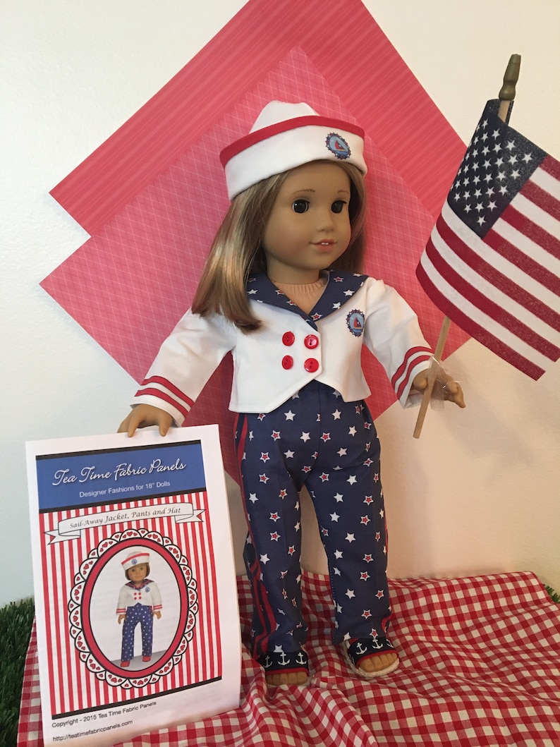 May include: A doll dressed in a sailor-themed outfit, including a white jacket with red buttons, navy pants with white stars, and a matching hat. The outfit is paired with anchor-decorated shoes. A small American flag is held nearby.
