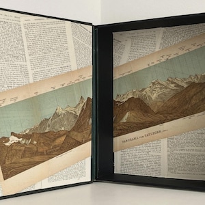 May include: A hollowed-out book box with a black exterior and a spine featuring printed illustrations. The interior panels are lined with vintage book pages and feature a diagonal mountain range illustration labeled Panorama vom Faulhorn.