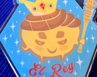 May include: A yellow cartoon character wearing a gold crown and holding a scepter. The character is surrounded by sparkling stars and the text "El Rey" is written in red below the character.