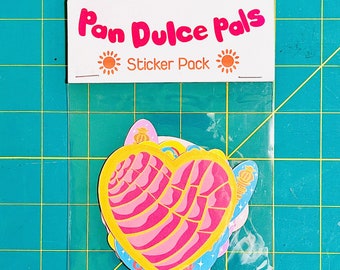 May include: A clear plastic bag with a white header that says "Pan Dulce Pals Sticker Pack" and features a sun on either side of the text. The bag contains a set of colorful stickers featuring a pink and yellow heart-shaped pan dulce.