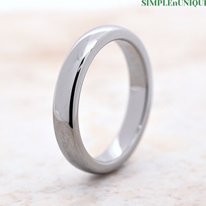 May include: A silver-toned wedding band with a polished finish. The band is simple and elegant, with a smooth, rounded surface.