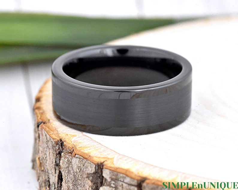 May include: A black tungsten carbide ring with a brushed finish. The ring has a beveled edge and a polished inner surface.