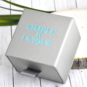 May include: A gray gift box with a drawer. The box has the text "SIMPLE & UNIQUE" printed on the front in blue.