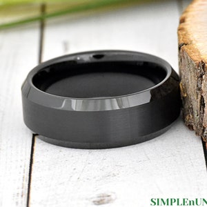 May include: A black, beveled, brushed, and polished tungsten carbide ring.