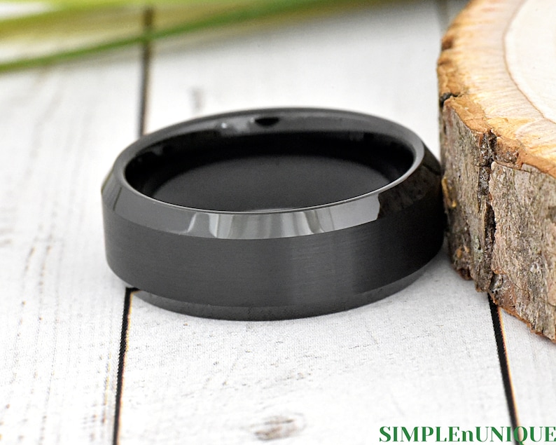 May include: A black, beveled, brushed, and polished tungsten carbide ring.